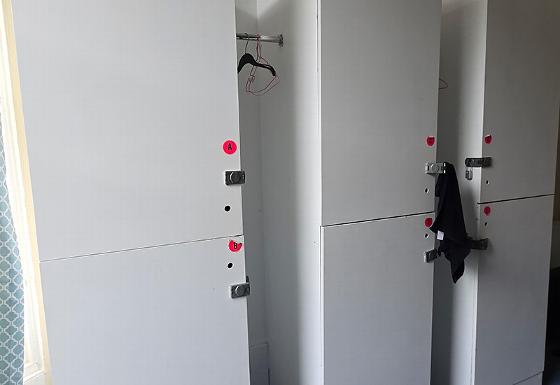 white lockers with hangers and clothing visible in a storage area for organization and convenience