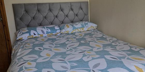 bed with decorative headboard and floral patterned bedding in a cozy room perfect for relaxation with two pillows arranged neatly