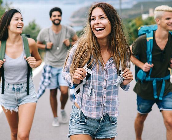 group of young adults hiking together on a sunny day enjoying outdoor adventure with smiles and backpacks 3 friends nature