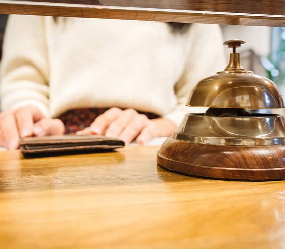 person's hands at a reception desk with a vintage bell and wallet background showing hospitality service 2 options